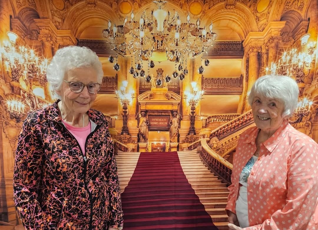 Two residents pose in front of an elegant Titanic exhibit backdrop.