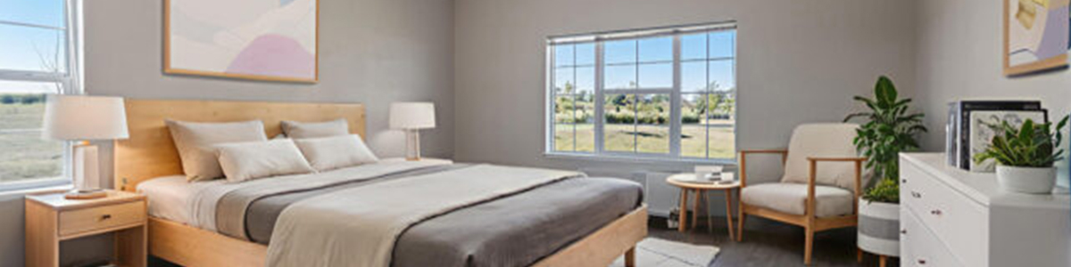 Bright, modern senior living bedroom at Stoney Point Meadows with large windows, neutral décor and comfortable furnishings.