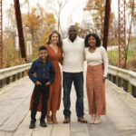 Group of four standing on a pedestrian bridge surrounded by fall foliage