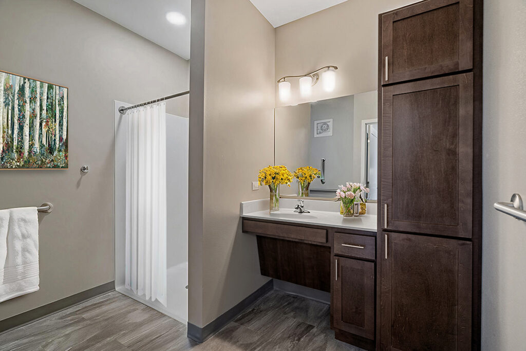 Apartment bathroom with vanity sink, mirror, tall storage cabinet, and walk-in shower with curtain at Stoney Point Meadows