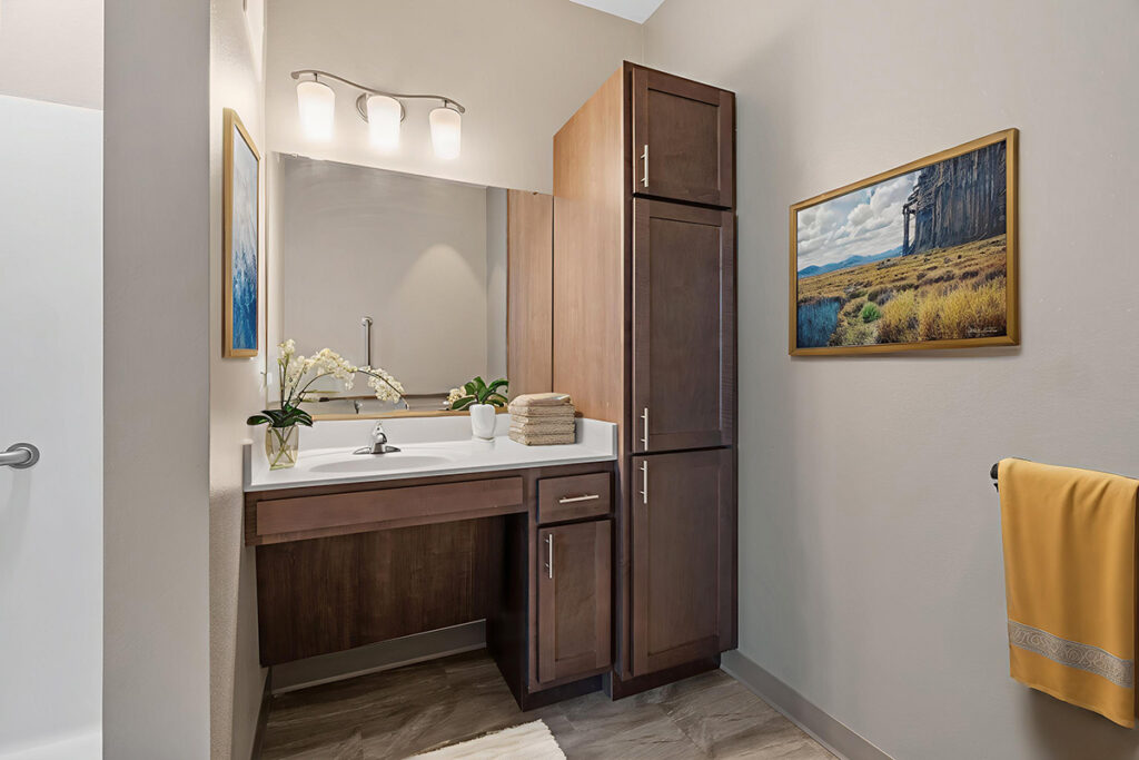 Apartment bathroom with vanity sink, mirror, tall storage cabinet, and decorative items in a clean, modern space at Stoney Point Meadows