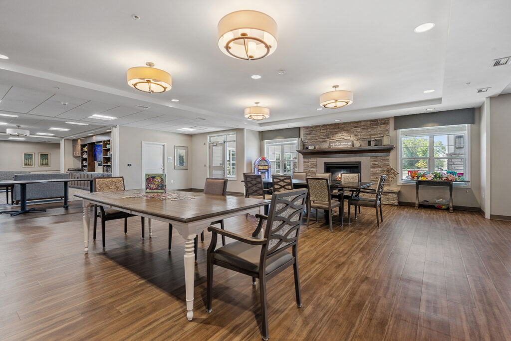 Spacious community game and lounge area with tables, chairs, fireplace, jukebox, and open seating areas at Stoney Point Meadows