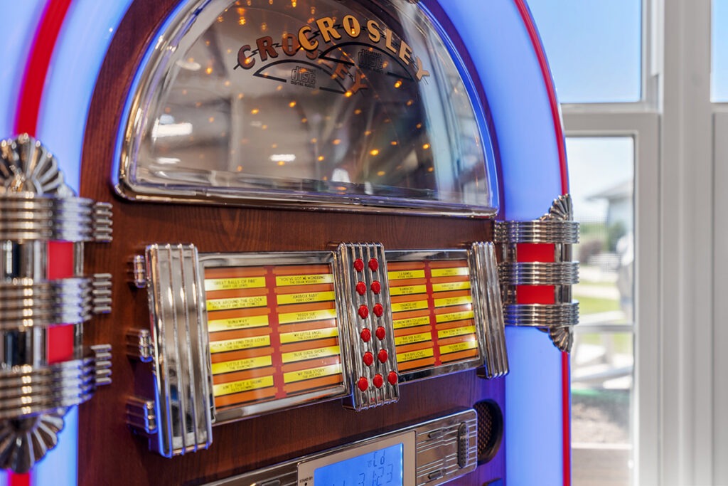 Close-up of a vintage-style jukebox with colorful lights, chrome accents, and song selection buttons near a window at Stoney Point Meadows