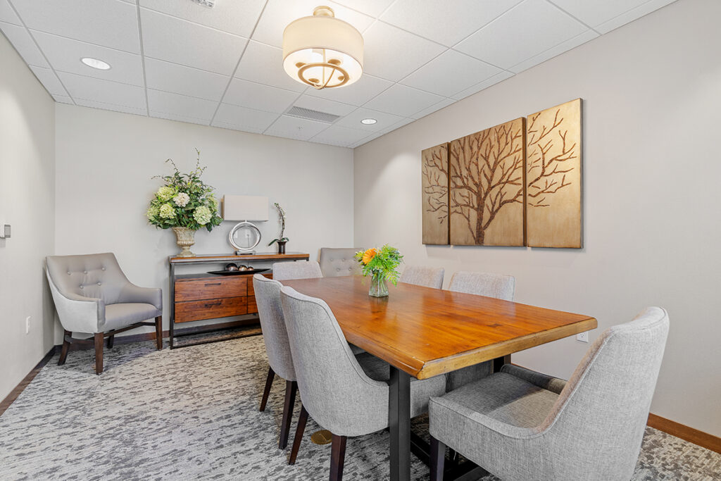 Private dining room with a wooden table, upholstered chairs, wall art, and decorative cabinet in a quiet setting at Stoney Point Meadows