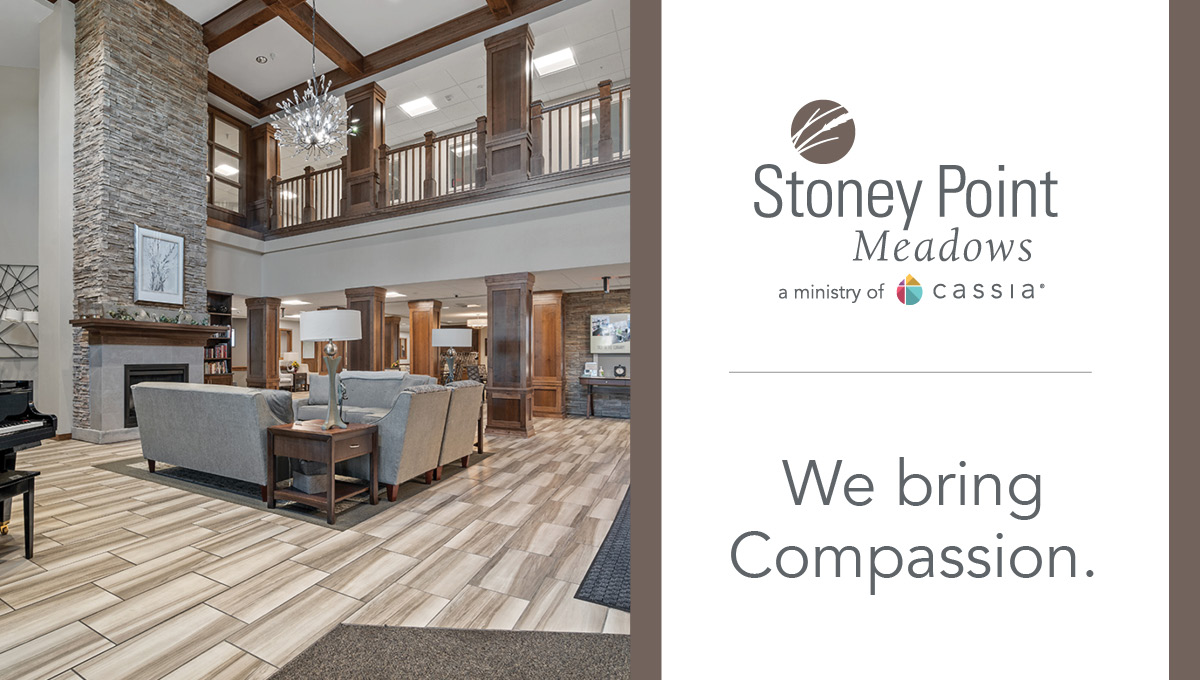 Stoney Point Meadows senior living community lobby with a stone fireplace, wood accents, comfortable seating, and the message: “We bring Compassion.”