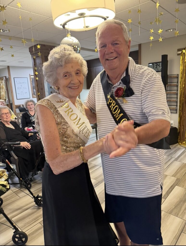 Prom queen and prom court member dance together during a prom-themed celebration.